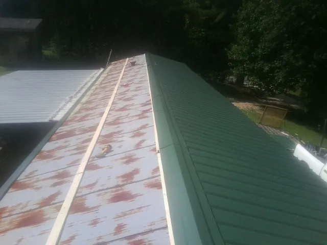 Old rusted panels beside newly installed green metal roofing — Wind Damage Roof Repair by Roofing Brothers in Nicoma Park