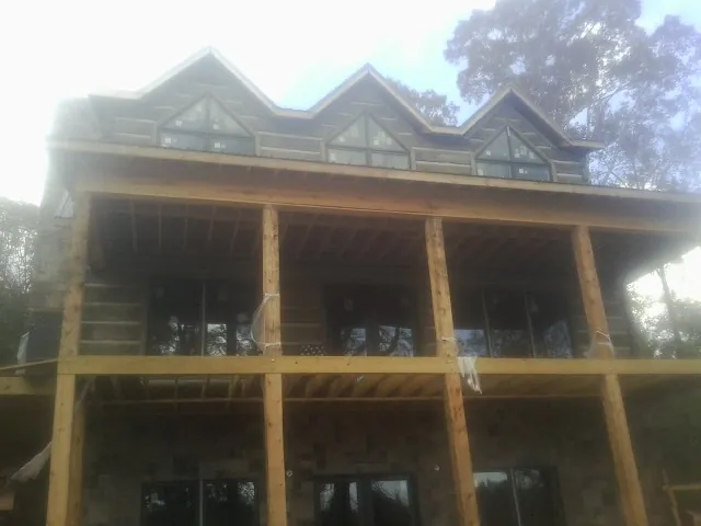 Dormers and porch framing on a large log home under construction — Roof Coating work by our crew in Nicoma Park
