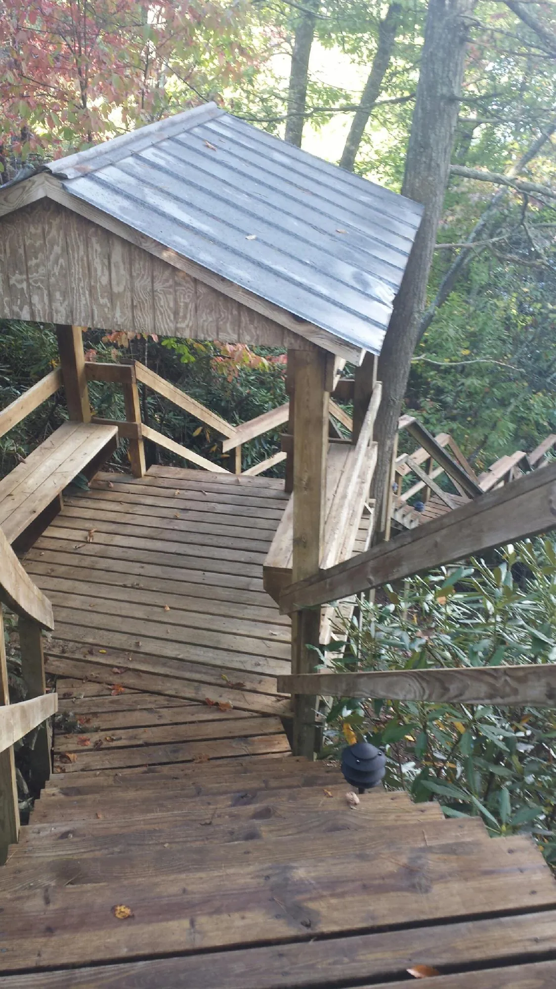 Metal roofed shelter over wooden steps on a wooded walkway — Skylight Repair & Installation work by our crew in Nicoma Park
