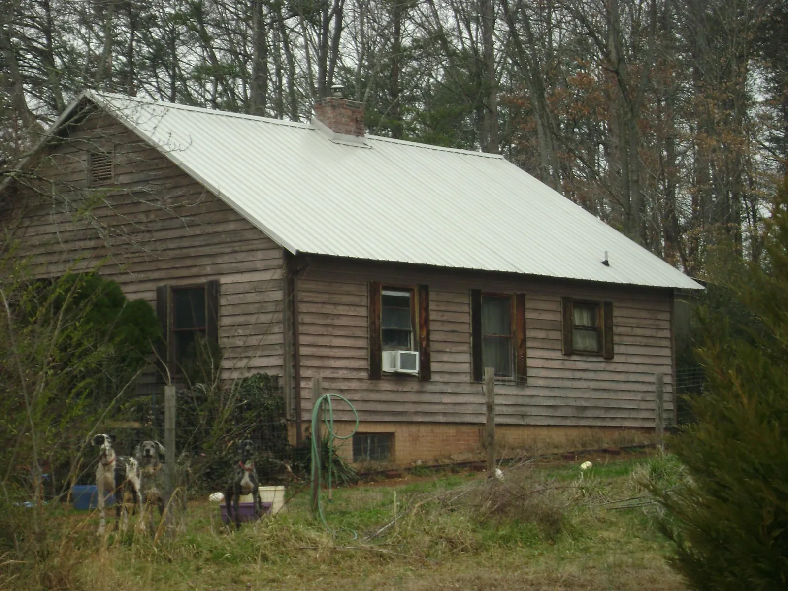 White metal roof on an old wood sided farmhouse, from a Metal Roof Installation job in Nicoma Park