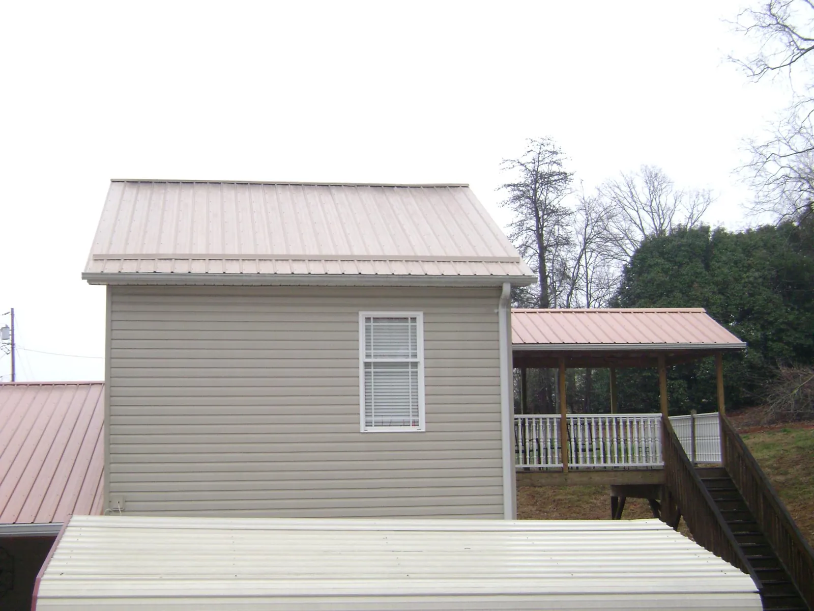 Tan metal roofs on a two story addition and attached porch, from a Roof Replacement job in Nicoma Park