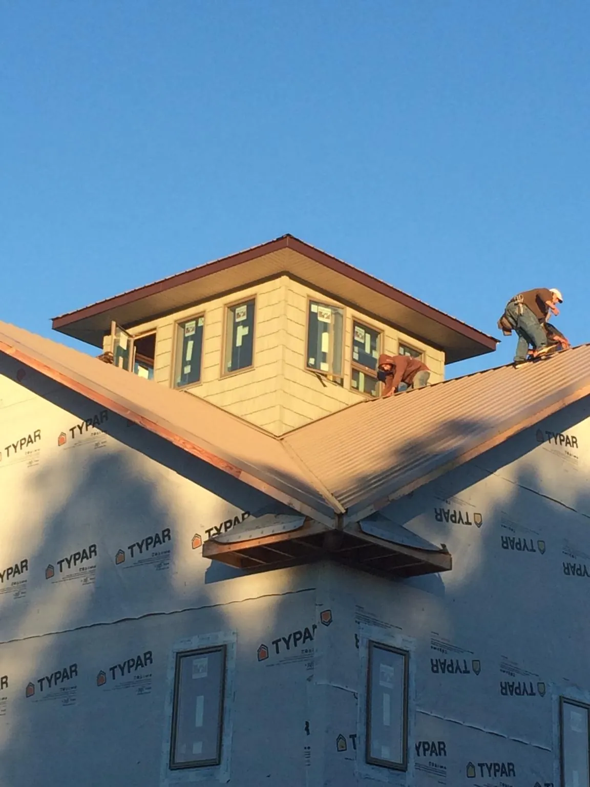 Roofers working around a rooftop cupola on a new metal roof at sunset — Roof Waterproofing in Nicoma Park by Roofing Brothers
